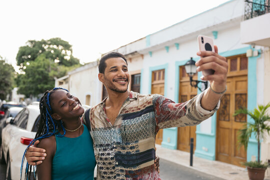 Friends taking selfies with smartphone while walking down the streets