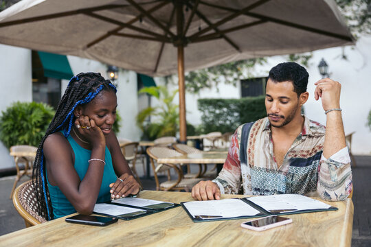 Friends reading the menu at an outdoor restaurant in the morning.