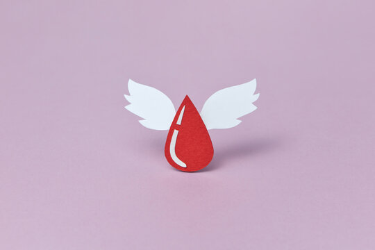 Red papercraft blood droplet with two white wings in studio
