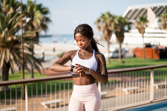 Young black woman in sportswear checking time on watch