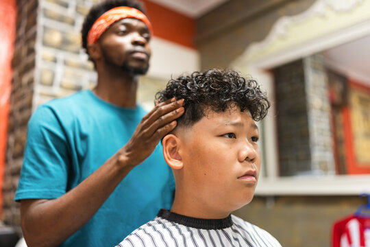 barber cutting the hair of a young asian boy