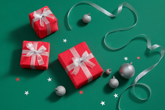 Overhead view of holiday boxes and Christmas baubles on a green 