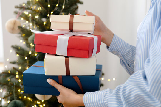A young woman holds several colorful boxes with Christmas gifts