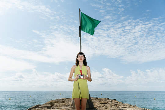 Woman standing with a vintage camera at the beach