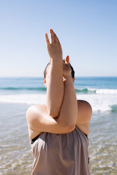 A young woman doing yoga at a beach