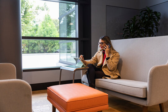 Confident Businesswoman drawing on tablet computer with cell phone