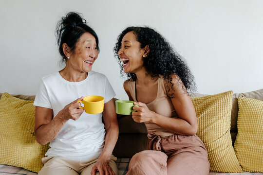 Senior mother and daughter chatting over cup of tea