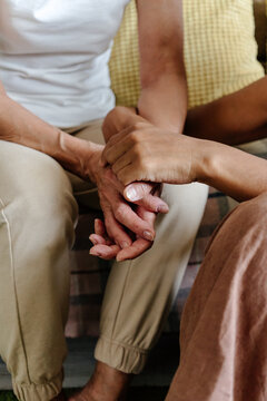 Crop senior mother and adult daughter holding hands