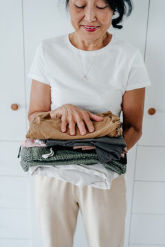Elderly woman with stack of clothes