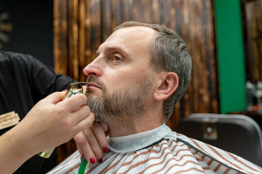 man having his beard cut by electric shaver