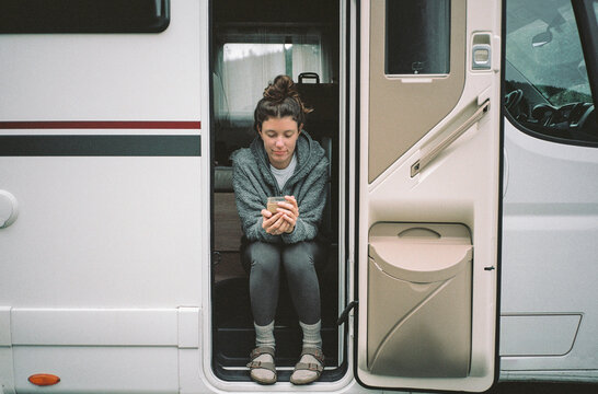 Young woman sitting at the entrance in camper van