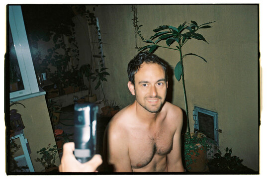 Hand passing an electric razor to a man smiling