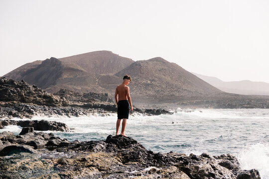 A portrait of a young man in Bermuda, standing on the rocky seashore