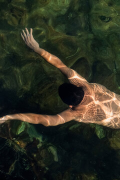 Aerial view of a person swimming in shallow, crystal-clear waters