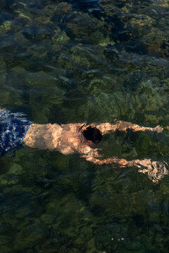 Overhead perspective of an individual swimming in crystal-clear water