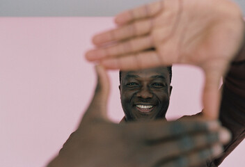 A portrait of a young smiling man over pink background