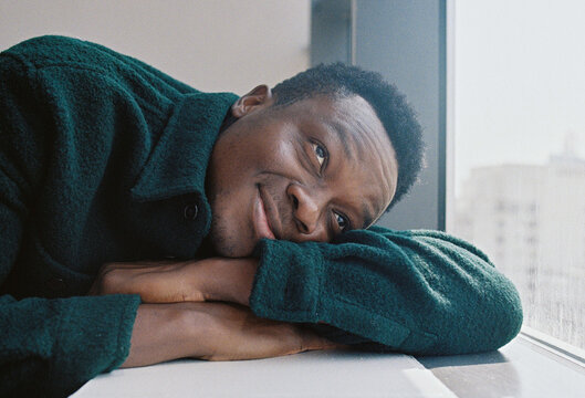 A portrait of a young man leaning by the window