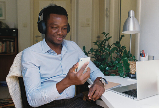 A man with a mobile phone sitting by the computer at home