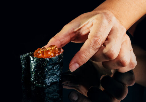Anonymous person taking delicious gunkan maki in studio