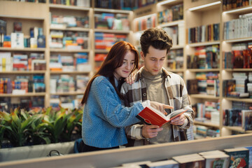 Affectionate young couple reading book together in cozy library.
