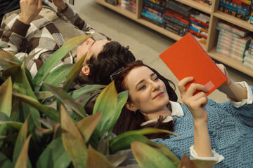 Young couple relaxing among plants in a bookstore browsing books together.