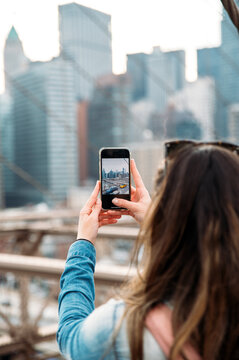 Woman capturing Manhattan skyline from Brooklyn Bridge