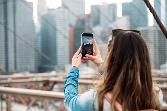 Woman capturing Manhattan skyline from Brooklyn Bridge