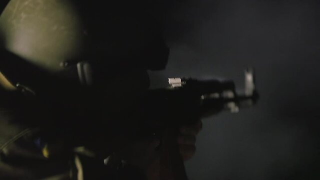 AMBIENT SOUND in video. Soldier shoots at an enemy with a machine gun at night. Male soldier aims a machine gun at nigh. Night battles in modern warfare. Military team fighting in the dark time shoot