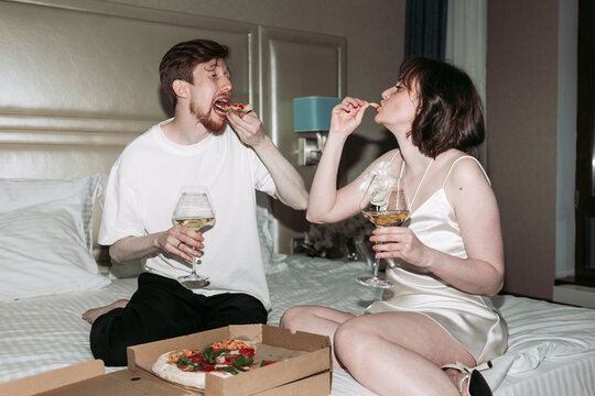Wedding day, couple sitting on bed and eating pizza 