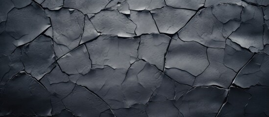 Close-up of cracked cement surface, providing a dark grey textured wallpaper.
