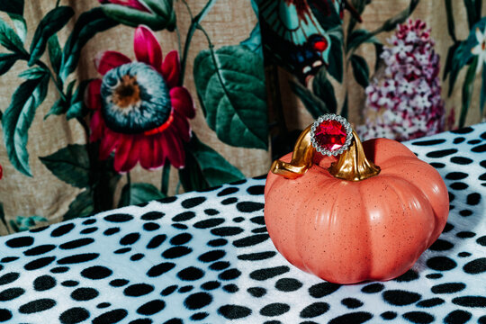pink pumpkin wearing a ring with a red gemstone 