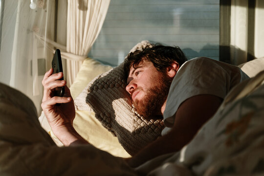 Man checking phone in bed