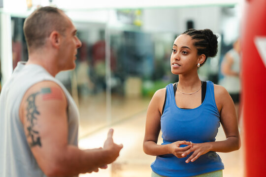 Smiling Ethiopian woman talking to trainer in gym