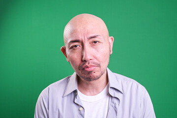 Obraz premium Portrait of Sad Asian Man Isolated on Green Background. Mental Health Concept. 