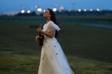 A Caucasian bride in a wedding dress plays the Ukulele - a Hawaiian four-stringed guitar variety...