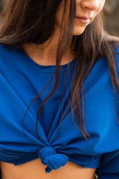 Woman wearing blue sweatshirt with knot on belly