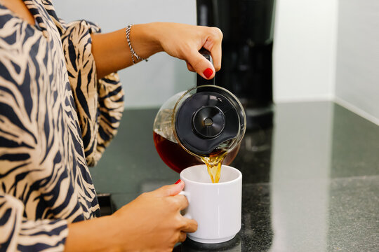 Close-up of a woman pouring a cup of coffee