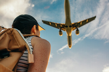 A traveler looks at a plane flying close