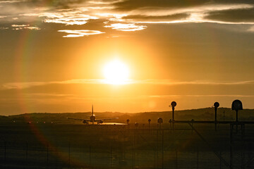 A passenger plane is preparing to take off on the runway at sunset