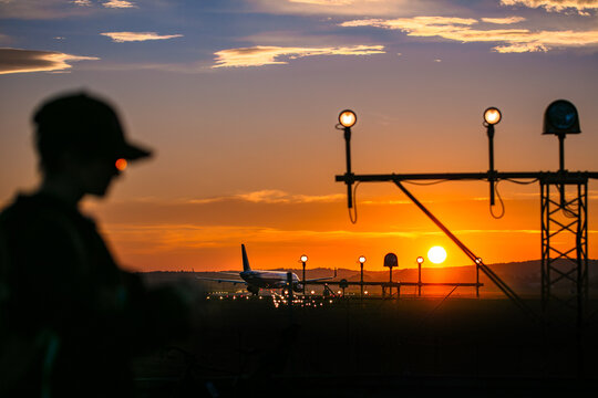 Silhouette of a man in a sunset airport with a plane on the runway
