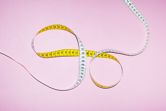 Measurement tape with hard direct flashlight on a coloured background