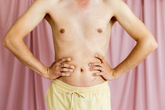 Close-up of the nude torso of a very thin man squeezing his stomach