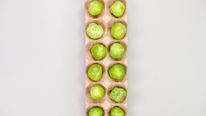 Raw organic Brussel sprouts in brown egg container on grey background, top view. Flat lay, overhead, from above. Copy space.