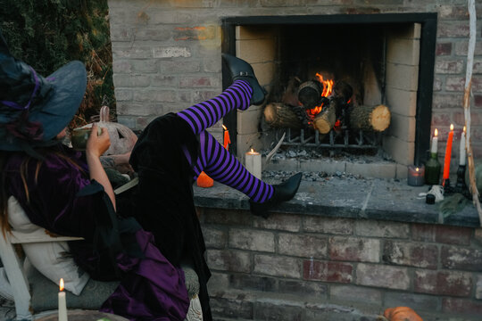 witch kicks feet up on hearth while enjoying a beverage