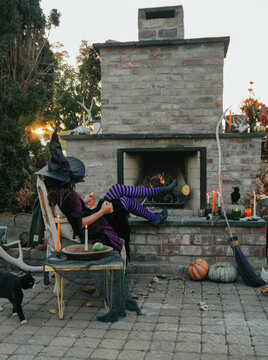 black cat walks by witch relaxing by fireplace