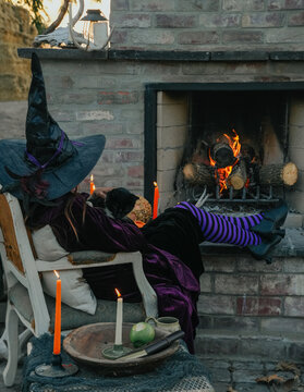 witch snuggles with her black cat near outdoor fireplace