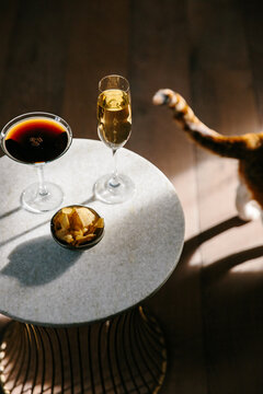 Alcoholic drinks on a table and a passing cat.