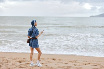 Beach Bliss: Young Woman Walking Alone on Sandy Coastline, Enjoying the Sunset in Stylish Hat