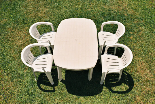 Top view of a white plastic table and four chairs on a lawn background