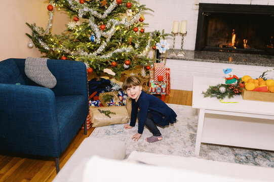 happy girl on christmas morning by the tree looking at presents